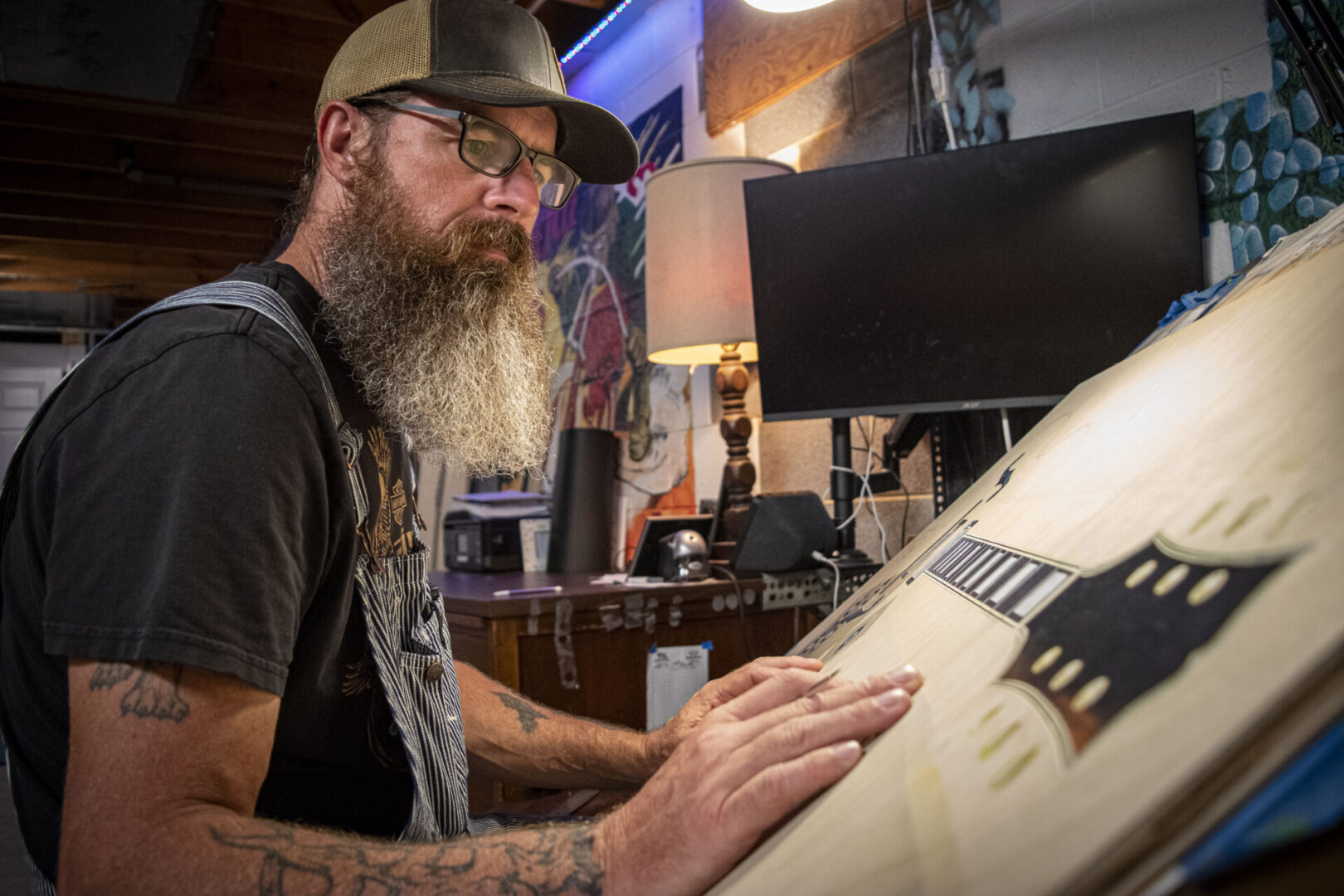 A man with long beard and glasses working on a computer.